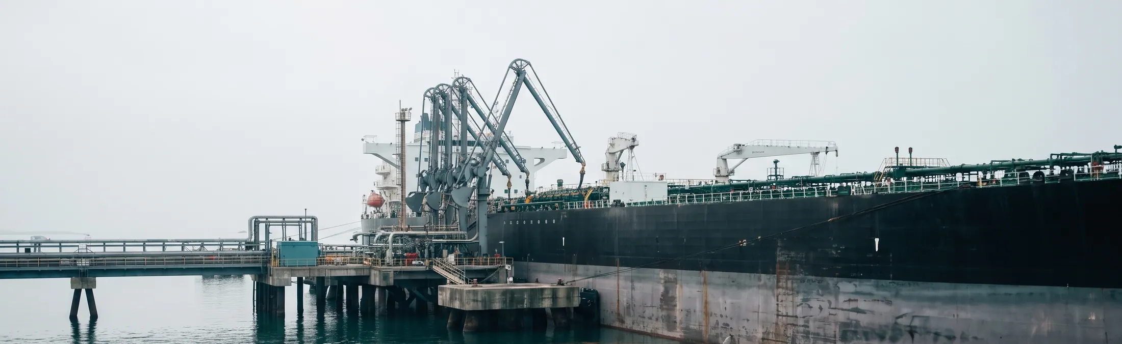 Tanker at its berth with loading arms on the pier